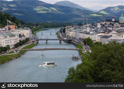 SALZBURG, AUSTRIA - JULY 9, 2016: Tourists floating on boat along historical city center of Salzburg.