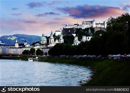 SALZBURG, AUSTRIA - JULY 9, 2016: Tourists walking along river bank in historical city center of Salzburg.