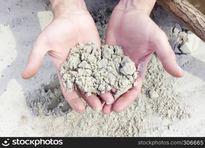 Sample of wet white quartz sand in male hands closeup. Selective focus, unrecognizable person.. White Quartz Sand In The Hands