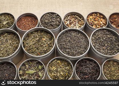 samples of loose leaf green, white, black red, and herbal tea in metal cans on canvas background