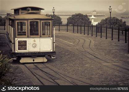 San Francisco cable car at Hyde Street turntable (Fisherman's Wharf) with foggy Aquatic Park in background, sepia toned image