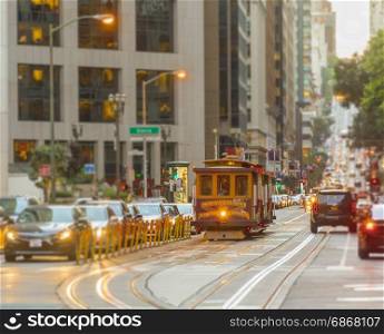 San Francisco Cable Car on focus with blurred traffic on California Street at sunset