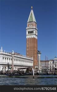 San Marco (St Mark's Square) in Venice in northern Italy. The Campanile, the clock tower and the Biblioteca Marciana (Library of St Mark), with gondolas on the waterfront to the lagoon.