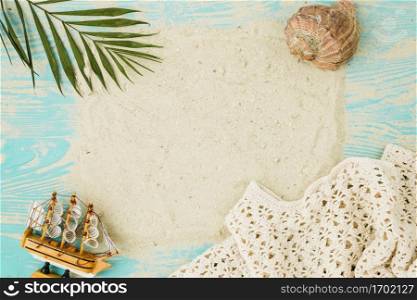 sand among plant leaf near seashell toy ship board