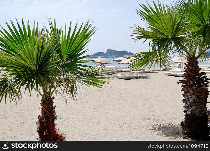 sand beach with palm trees in Fethiye, Turkey, sea and island in the distance