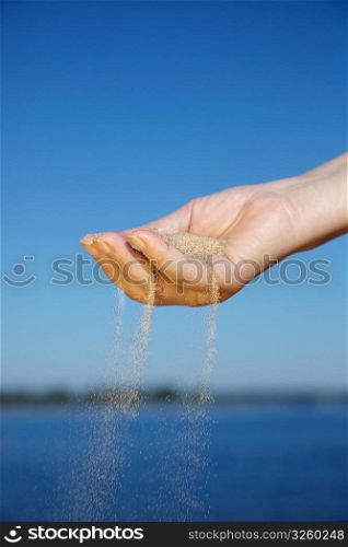 Sand falling from woman&acute;s hand, selective focus on nearest part