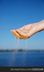 Sand falling from woman&acute;s hand, selective focus on nearest part