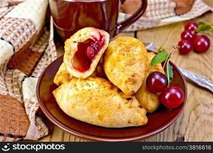 Sand pies with cherries on a plate, cup, napkin on a wooden boards background