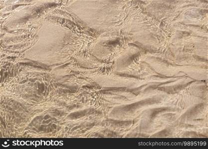 Sand underwater background texture. Clear ripple sea wave and white sand. Top view