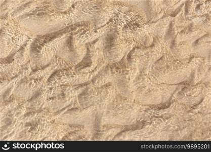 Sand underwater background texture. Clear ripple sea wave and white sand. Top view