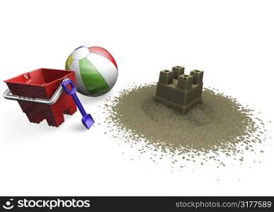 Sandcastle with beach ball, bucket and spade