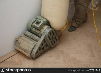 Sanding a new wooden floor with a heavy machine
