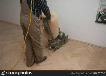 Sanding a new wooden floor with a heavy machine