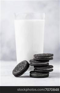 Sandwich black cookie consisting of two chocolate wafers with cream filling with glass of milk on stone board.