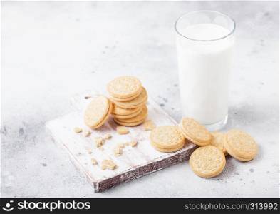 Sandwich cookie consisting of two chocolate wafers with cream filling with glass of milk on stone board.