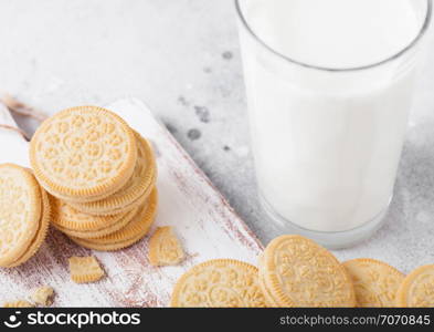 Sandwich cookie consisting of two chocolate wafers with cream filling with glass of milk on stone board.