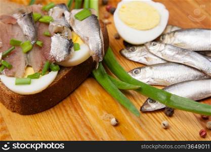 sandwich from salted anchovies with egg and spring onion on wood