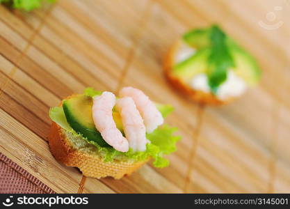 Sandwich garnish with shrimps, avokado and lettuce on bamboo napkin, snack