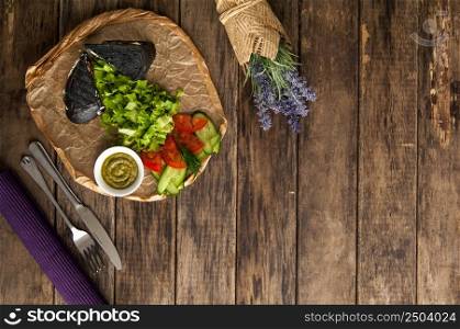 sandwich of black bread with vegetables on a wooden surface. sandwich on wooden surface