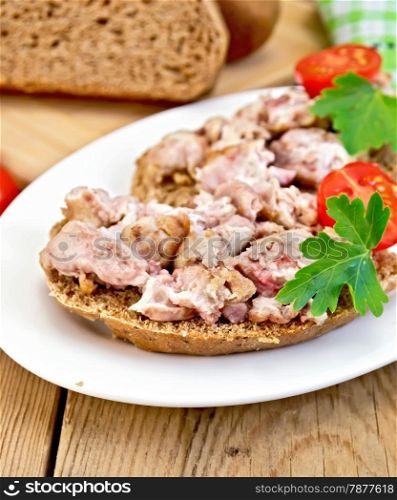 Sandwich of rye bread, brains, tomato and parsley on an oval plate on a wooden boards background