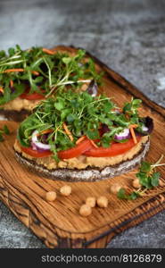  Sandwich toasted rustic bread with chickpea hummus, tomato slices, mix of lettuce and microgreens. Vegetarian breakfast. 