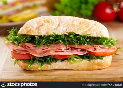 sandwich with bacon and vegetables on wooden table