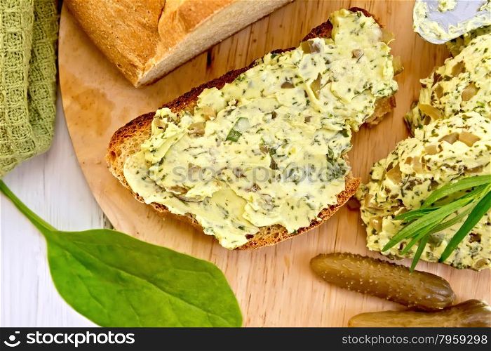 Sandwich with butter from butter, spinach and pickles, a knife, a bowl with butter, cloth, bread of wooden board background on top