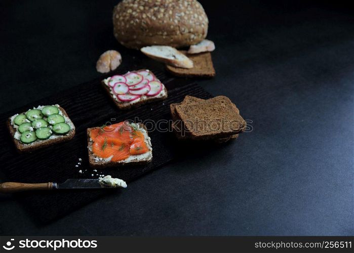 Sandwich with cereals bread smoked salmon beetroot and cucumber on dark marble background