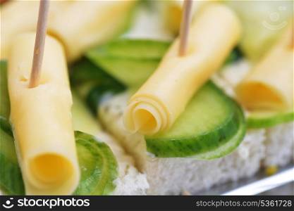 Sandwich with cheese and cucumber on wooden chopsticks