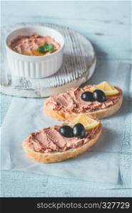 Sandwich with chicken liver pate and black olives on the white parchment