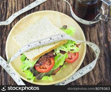 Sandwich with cold soft drink and measurement tape as diet concept