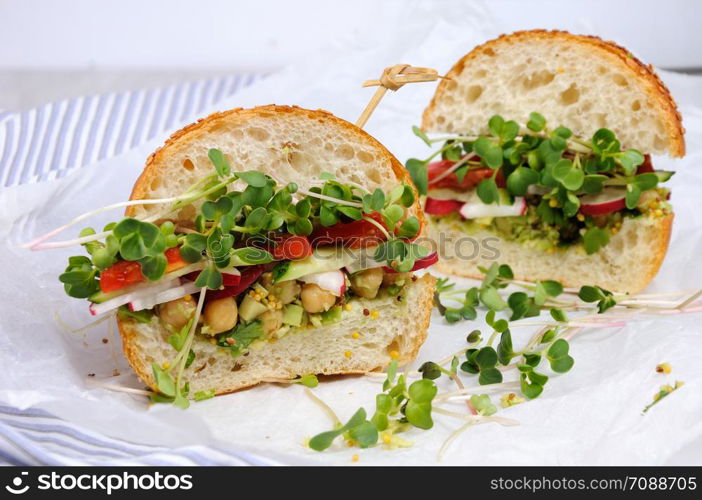 Sandwich with green radish sprouts crispy radish and cucumber, tomato with avocado dressing and mustard with herbs.