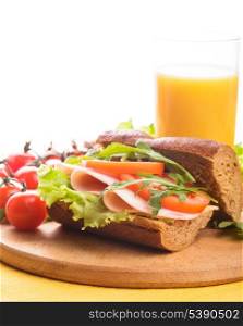 Sandwich with ham, tomato, lattuce and arugula with glass of orange juice with copy space.