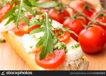 Sandwich with mozzarella, tomato, arugula and pesto