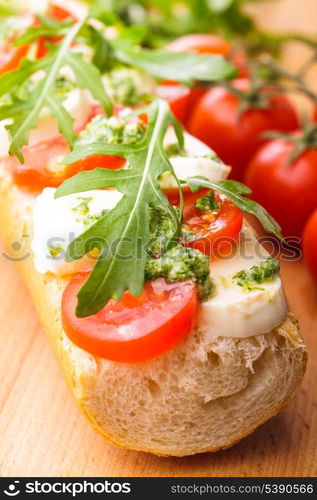 Sandwich with mozzarella, tomato, arugula and pesto