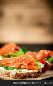 Sandwich with salmon on a wooden background. High quality photo. Sandwich with salmon on a wooden background.