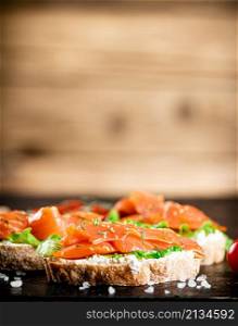Sandwich with salmon on a wooden background. High quality photo. Sandwich with salmon on a wooden background.