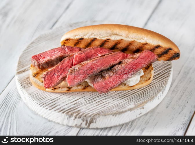 Sandwich with sliced beef steak and ricotta on wooden board