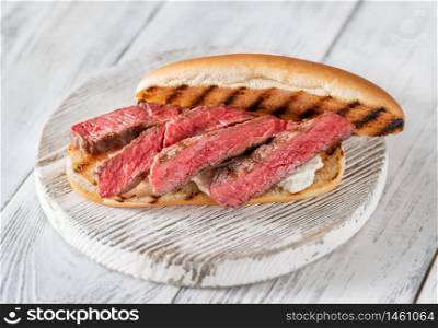Sandwich with sliced beef steak and ricotta on wooden board