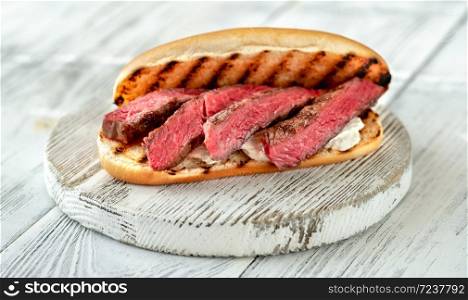 Sandwich with sliced beef steak and ricotta on wooden board