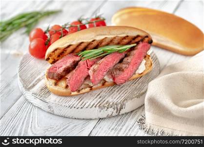 Sandwich with sliced beef steak, ricotta on the wooden board