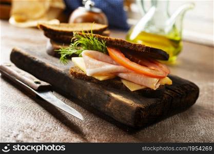 Sandwich with tasty ham on wooden board