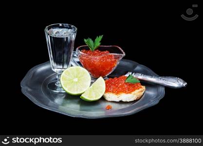 Sandwiche with red caviar, glass of vodka, sliced lime and old knife on a tin plate