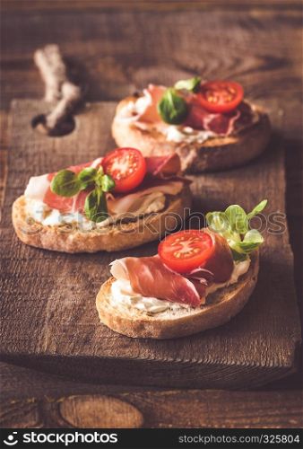 Sandwiches with cream cheese and ham on the wooden board