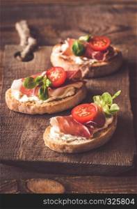Sandwiches with cream cheese and ham on the wooden board