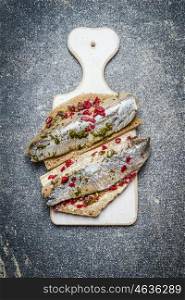 Sandwiches with herring on a white cutting board, top view