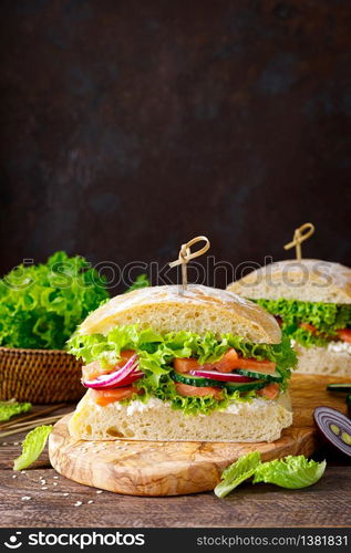 Sandwiches with homemade ciabatta bread, salted salmon fish, feta cheese, cucumber, onion and fresh lettuce salad, italian cuisine