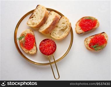 Sandwiches with red caviar and bread in a round plate on a white table, top view