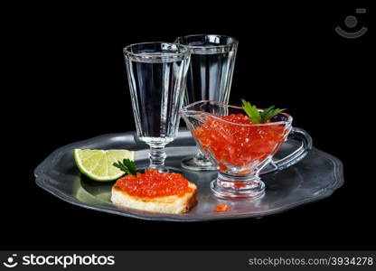 Sandwiches with red caviar and two glasses of vodka on a pewter plate isolated at black