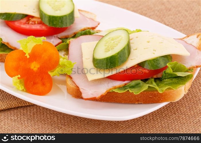 Sandwiches with rusks, vegetables, bacon and cheese on plate.